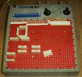 DeVry breadboard.  A sloping front chassis with red plastic panels (with holes into which white modular connectors can be inserted.