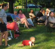 Concert-goers watching a baby crawl toward the action