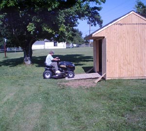 Sue drives the mower up the ramp into the shed.
