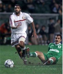 Qatar's Mubarak Mostafa Fazli (L) controls the ball as Palentine's Saeb Jendeya falls.